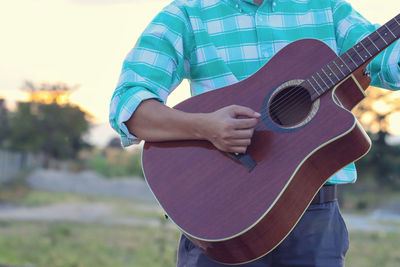 Midsection of man playing guitar at yard