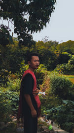 Side view of young man standing against plants