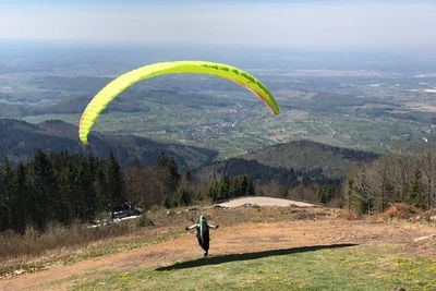 Man paragliding over mountain against sky