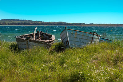 Abandoned boat in sea against clear blue sky