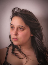 Thoughtful woman looking away against wall