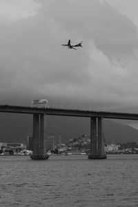 Airplane flying over river against sky