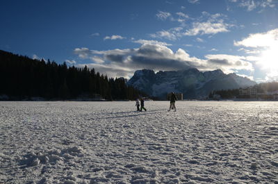 People on snow covered landscape against sky