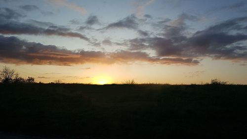 Scenic view of silhouette field against sky at sunset
