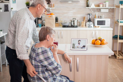 Senior couple video conferencing with doctor over laptop on table