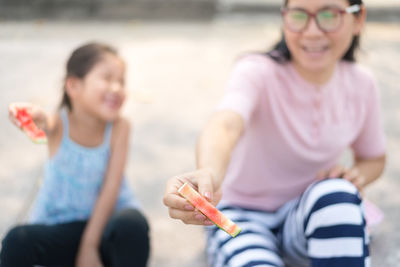 Mother and daughter showing eaten watermelon slices while sitting outdoors