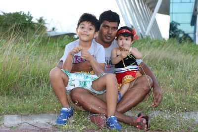 Portrait of father with kids sitting on grass