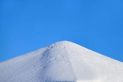 Low angle view of snowcapped mountain against clear blue sky