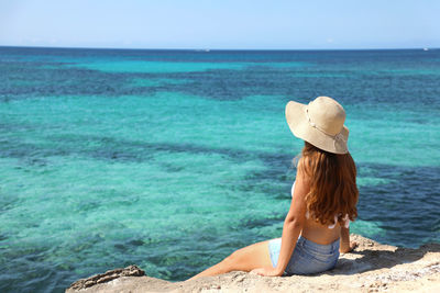 Woman wearing hat looking at sea against sea