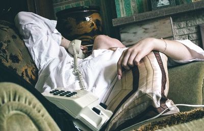 Midsection of girl talking on landline phone while lying on sofa