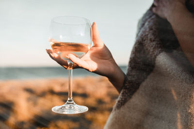 Young woman with a wine glass in a field at sunset