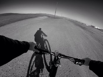 Man with bicycle on road against sky