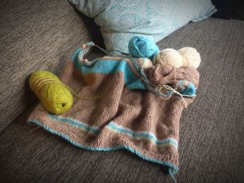 Close-up of crochet with colorful wool on sofa