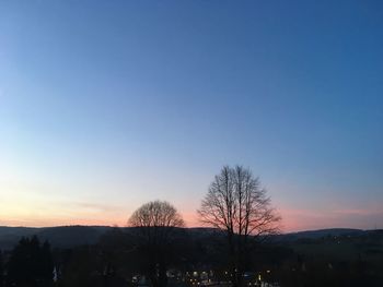 Silhouette bare trees against clear sky at sunset