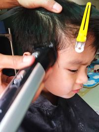 Cropped hand cutting boy hair at salon