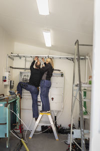 Male and female electrician fixing cables in meter room at industry