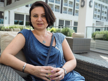 Portrait of mature woman having drink while sitting on chair