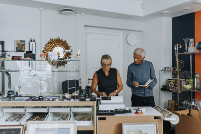 Male and female owners standing at checkout while working in antique shop