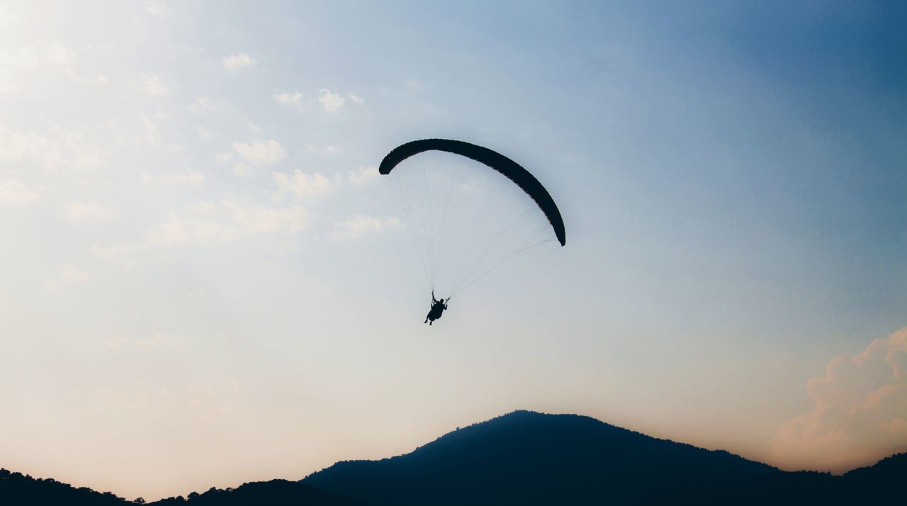 mid-air, silhouette, sky, nature, sunset, real people, adventure, flying, extreme sports, parachute, low angle view, mountain, outdoors, leisure activity, beauty in nature, scenics, one person, paragliding, lifestyles, day, people