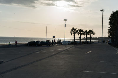 Road by sea against sky during sunset