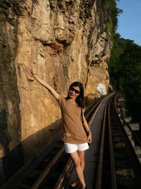 Portrait of smiling mature woman with arm raised standing on railway bridge 