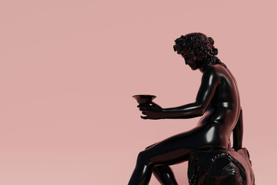 Low angle view of statue against pink background