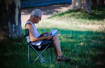 Side view of a man sitting on grass