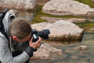 Photographer against rocks in lake