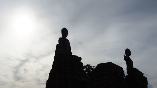 Low angle view of silhouette statue against building against sky