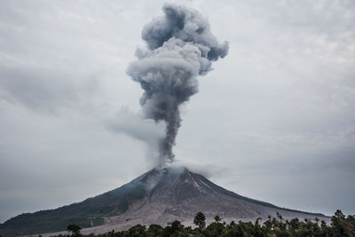 Smoke emitting from volcanic mountain against sky