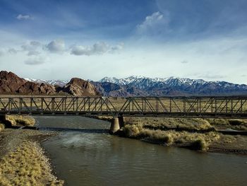 Bridge over river by mountain against sky