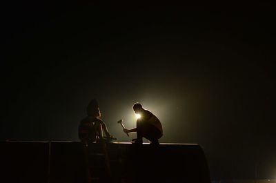 Silhouette men sitting on stage