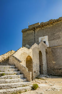 Low angle view of old building against clear blue sky