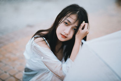 Portrait of young woman with umbrella sitting outdoors