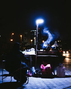 People sitting on illuminated street at night