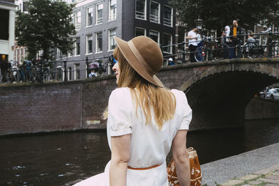 Rear view of woman standing on bridge over canal