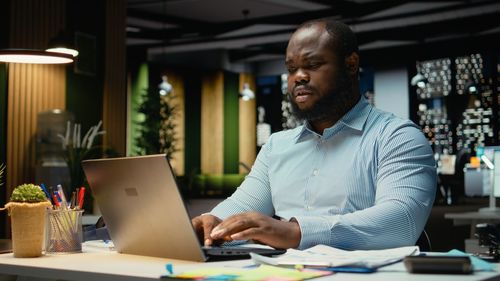Young man using laptop while sitting on table
