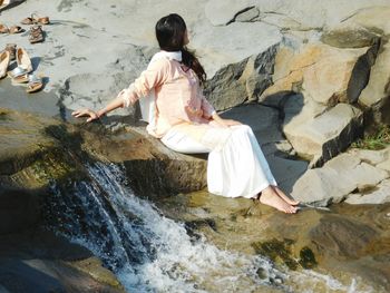 Woman sitting on rock by sea