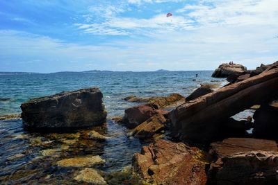 Rocks on shore by sea against sky
