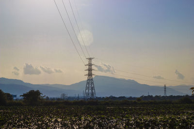 Electricity pylon on field against sky during sunset