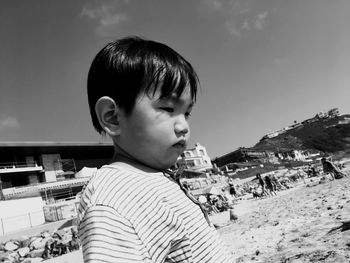 Boy looking away while standing on beach