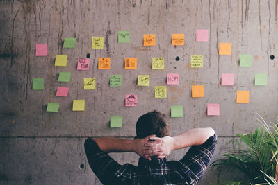 Rear view of man looking at adhesive notes in office