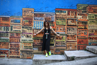 Full length of woman standing against mural on wall