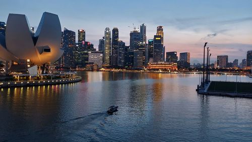 Illuminated buildings in city against sky during sunset