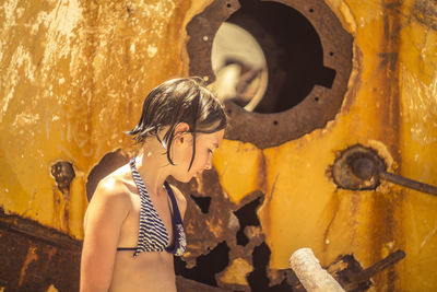 Close-up of girl standing against rusty metal