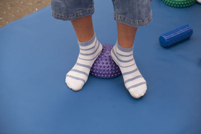 Low section of boy wearing socks standing on spiked balls while exercising in gym