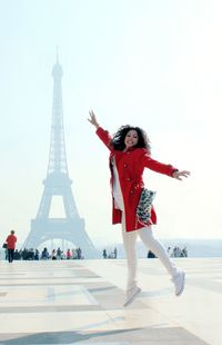 Portrait of smiling young woman jumping against eiffel tower