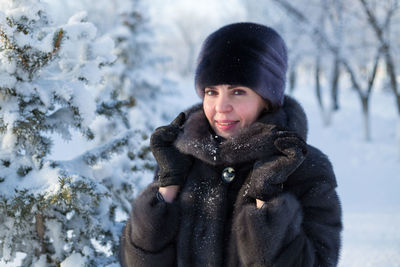 A woman in a mink fur coat and a hat with a smile stands against the background 
