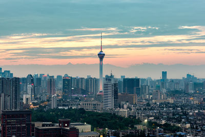 Modern buildings in city against sky during sunset