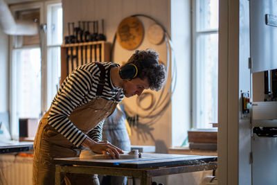 Side view of young woman using mobile phone while sitting at home